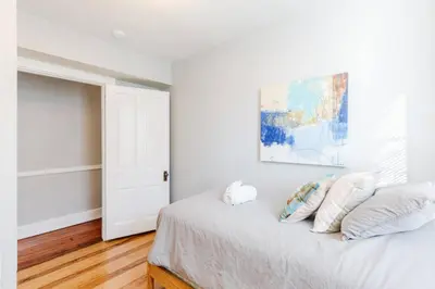 a white bedroom with a bed with pillows and a painting at 2 Large Apts w Parking - Downtown Over the Rhine in Cincinnati