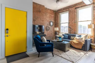 a yellow door in a living room with a brick wall at Entire Historic Building Sleeps 30 in Cincinnati