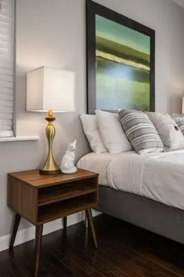 a bedroom with a bed and a table with a lamp at Two Comfy Condos Near City Center OTR UC Zoo in Cincinnati