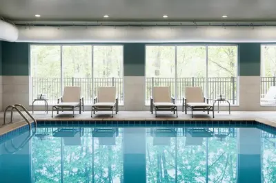 a pool in a hotel with chairs and windows at Holiday Inn Express & Suites Lima by IHG in Lima