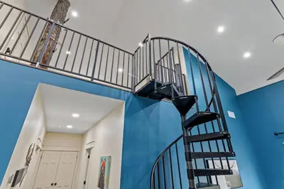 a spiral staircase in a room with a blue wall at New Barndo/Private River Access/ 2 Private Hot Tub in Stanton