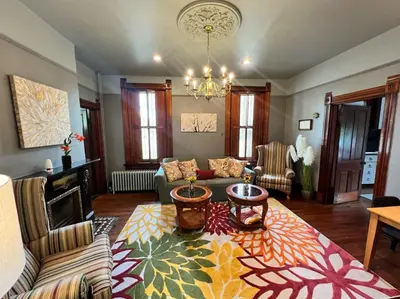 a living room with a couch and a chandelier at Skyline Retreat Spacious Elegance Queen Suite 3 City Views in Cincinnati