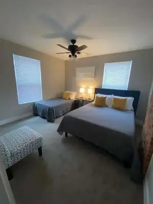a bedroom with two beds and a ceiling fan at 2 homes side by side downtown with fenced yard and hot tub in Columbus