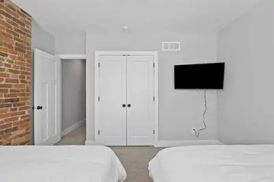 a white bedroom with two beds and a flat screen tv at Massive home downtown with Hot Tub in Columbus