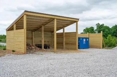 a large woodenshed with a blue recycling container at Block of 7 Lodges at Eden Reserve - For Groups in Williamstown