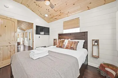 a bedroom with a large bed and a television at The Lodges at Eden Reserve - Cabins Near Ark in Williamstown