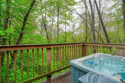 a hot tub on a wooden deck with trees at Blue Rose Cabins - Wildwoods Cabin in Logan