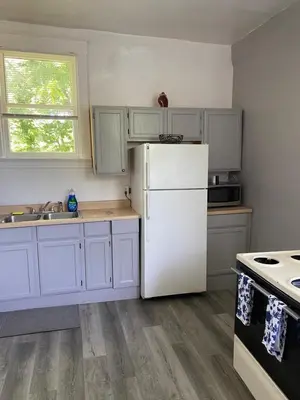 a kitchen with white cabinets and a white refrigerator at Second floor petite studio private room in Cincinnati