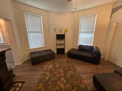 a living room with black leather furniture and windows at Second floor petite studio private room in Cincinnati