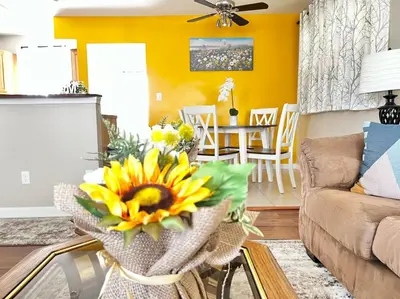 a living room with yellow walls and a vase of sunflowers at Sunny Stay Bright and Cozy Suite 2 in Cincinnati