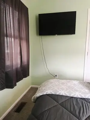 a bedroom with a bed and a flat screen tv on the wall at Blue Heron Cottage with Game Room, Deck, Hot Tub in Logan
