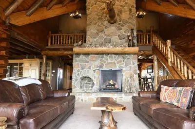 a living room with leather couches and a stone fireplace at Coschocton Hills - 2 Luxury Log Cabins - Lake in Coshocton