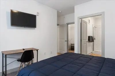 a bedroom with a bed and a desk and a flat screen tv at Cozy 10BR 10BA combined Apartment Near Downtown Cincinnati in Cincinnati