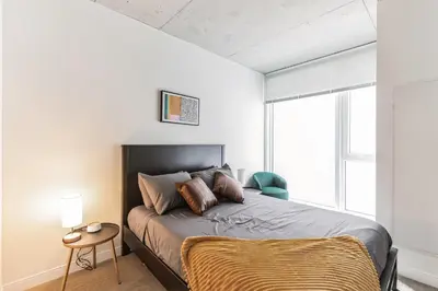 a bedroom with a bed and a chair and a window at Brand new 2BR 3BA combined apartments with city views in Cleveland