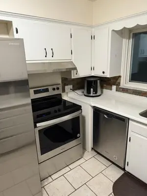 a kitchen with white cabinets and a stove top oven at The Unity Hub in Toledo