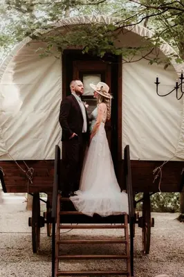a bride and groom are standing in a doorway at Luxury Conestoga Wagon, Perfect for a Weekend Glamping Escape from Dayton, Ohio