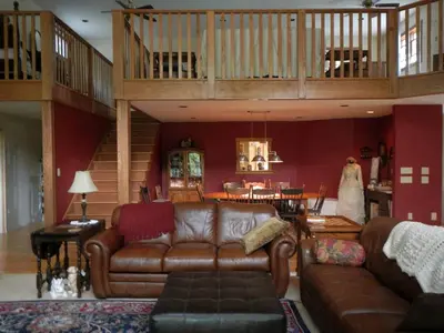 a living room with a leather couch and a staircase at Peaceful Getaway on a Lovely Farm near Hillsboro, Ohio