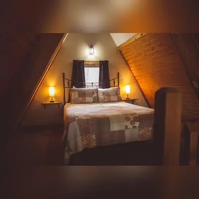 a bedroom with a bed with two lamps and a window at A-Frame #03 - by The Chalets in Logan