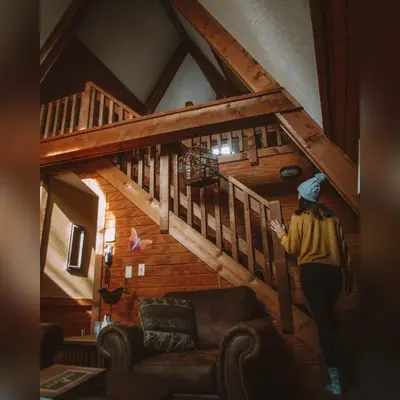 a woman walking up the stairs of a cabin at A-Frame #04 - by The Chalets in Logan