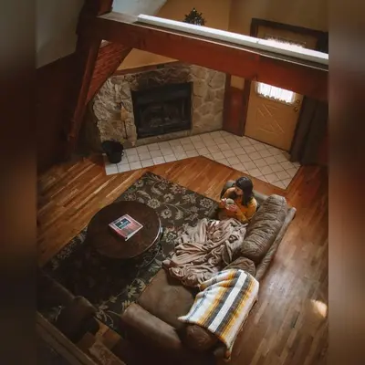 a person laying on a couch in a living room with a fireplace at A-Frame #06 - by The Chalets in Logan