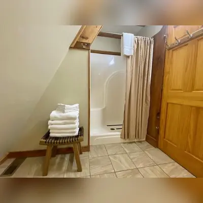 a bathroom with a shower and a pile of towels at A-Frame #07 - by The Chalets in Logan