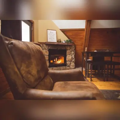 a leather couch in a living room with a fireplace at A-Frame #08 - by The Chalets in Logan