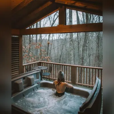 a woman sitting in a hot tub on a porch at A-Frame #09 - by The Chalets in Logan