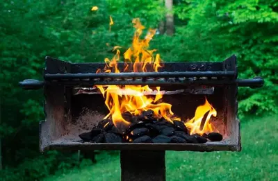 a grill with fire in it in a yard at A-Frame #14 - by The Chalets in Logan