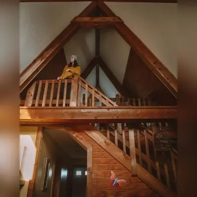 a woman sitting on top of a wooden staircase at A-Frame #16 - by The Chalets in Logan
