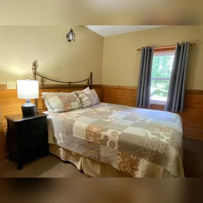 a bedroom with a bed with a lamp and a window at A-Frame #18 - by The Chalets in Logan