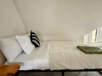 a bed with white sheets and pillows in a bedroom at Jungle House Columbus Sleep 12 Downtown Ohio Free Parking - Near Convention Center & Nationwide Arena - 4BR Short North Luxury Home - Over 5,800 Five Star Stays in Columbus