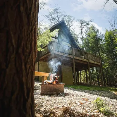 a person sitting over a fire in front of a house at Falls - by The Chalets in Logan