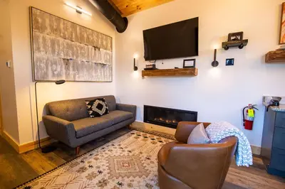 a living room with a couch and a tv on a wall at Legends Lane B - by The Chalets in Logan