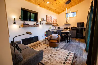a living room with a couch and a table and a kitchen at Legends Lane C - by The Chalets in Logan