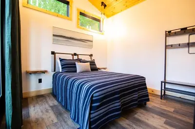 a bedroom with a bed with a blue and white striped blanket at Legends Lane C - by The Chalets in Logan