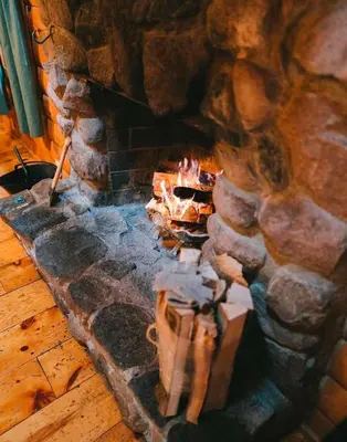 a stone fireplace with a fire in it at Pine Creek - by The Chalets in South Bloomingville
