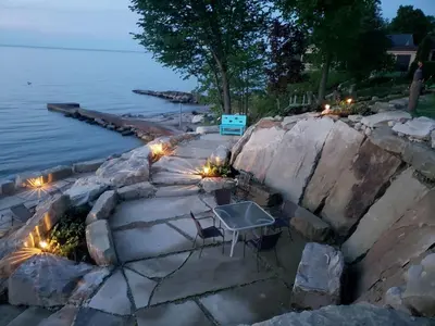 a patio with lights next to the water at night at Idyllic Beachfront Vacation Rental on the Shores of Lake Erie in Northern Ohio in Vermilion