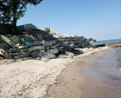 a beach with a rock retaining wall next to the water at Rustic Lakeside Vacation Rental with Beach Access in Vermilion, Ohio in Vermilion