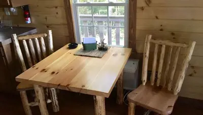 a wooden table and chairs in a room with a window at Romantic Log Cabin Accommodation with Private Jacuzzi near Huntington, West Virginia in Genoa