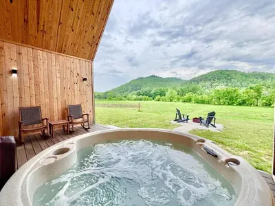 a hot tub on a deck with a view of a field at Knob Hill at Three Suns Cabins in Stanton