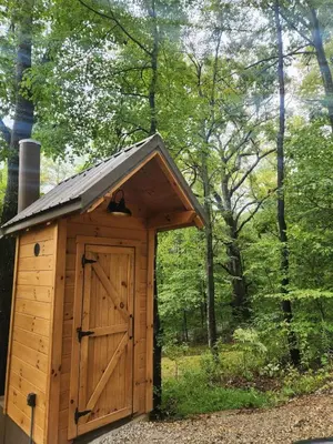 a wooden outhouse with a door in the woods at Romantic A-frame Cabin Ideal for Two by Tappan Lake in Ohio in Deersville