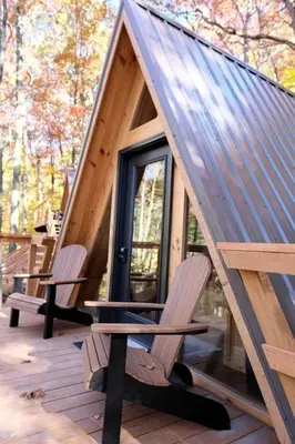 a house with two chairs and a table on a deck at Cozy Tree Cabin with Wonderful Views from the Deck by Tappan Lake in Ohio in Deersville