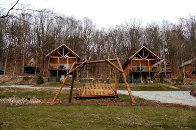 a park with a wooden swing in front of a house at Rustic Tree A-Frame with Original Design by Tappan Lake in Ohio in Deersville