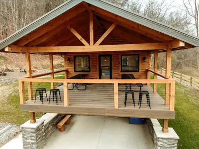 a log cabin with a deck with chairs and tables at Rustic Tree A-Frame with Original Design by Tappan Lake in Ohio in Deersville