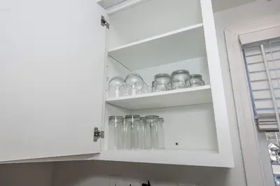 a kitchen cabinet filled with clear glass dishes at The Grand Elm Suites in Ludlow