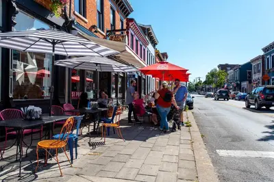 a group of people walking down a sidewalk with tables and umbrellas at Covington Charm 101 in Covington