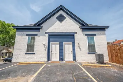 a white house with blue doors in a parking lot at Covington Charm 201 in Covington