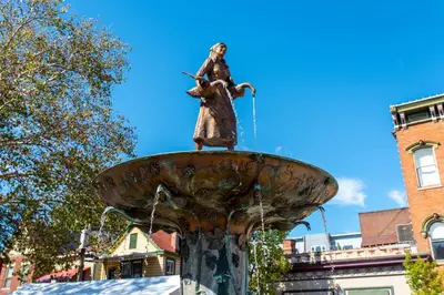 a statue of a woman standing on top of a fountain at Suites on Main 1 in Covington