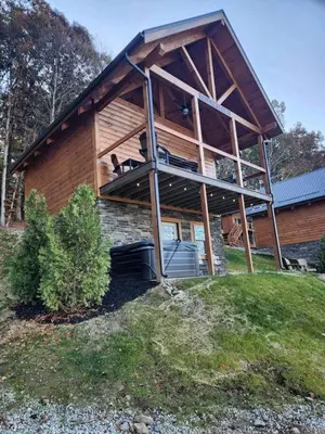 a house with a dog on the balcony of it at Group Friendly Cabin with Spa on the Deck near Tappan Lake in Ohio in Deersville