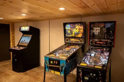 three video game machines are lined up in a room at Lakeview Cabin by Tappan Lake, Perfect for Groups with Hot-Tub in Ohio in Deersville